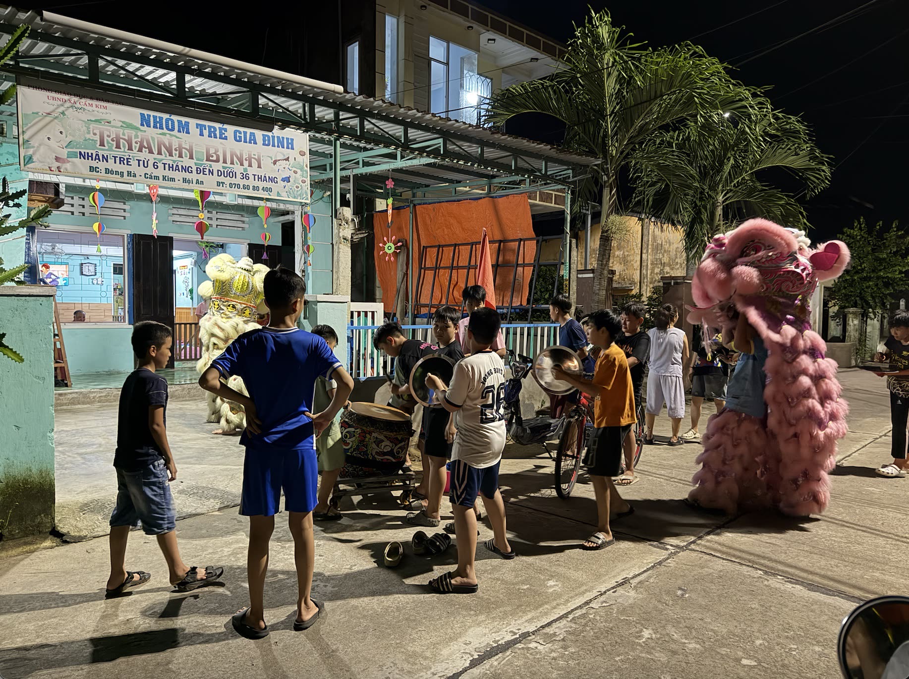 Vietnam'da gece bir sokakta aslan dansı kostümü ve çocuklar