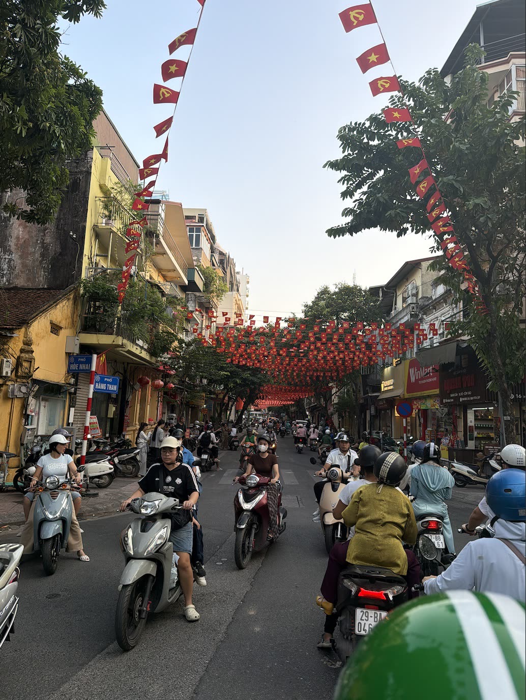 Hanoi'de bayraklarla süslü bir sokakta motosikletler