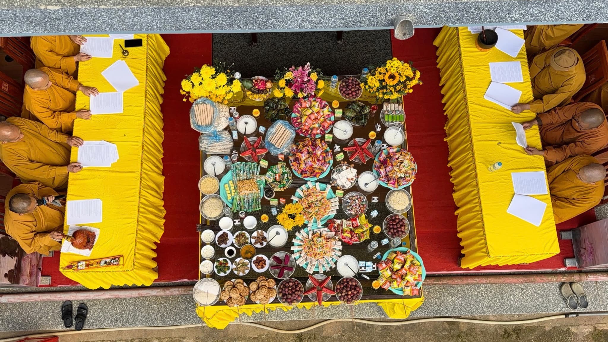 Tapınakta sunu masası ve dua eden Budist rahipler, yukarıdan